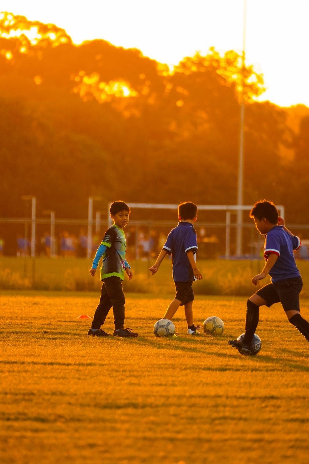 Children playing soccer on a sunny evening field