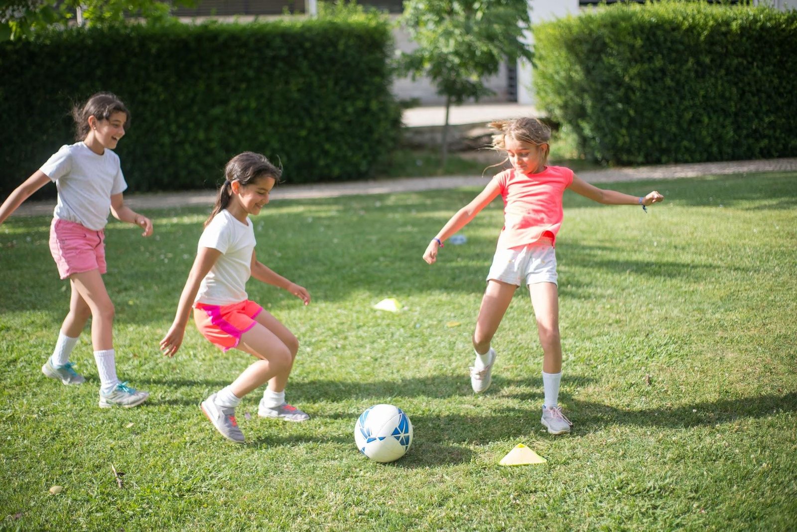 Young girls having fun playing soccer outdoors on grass