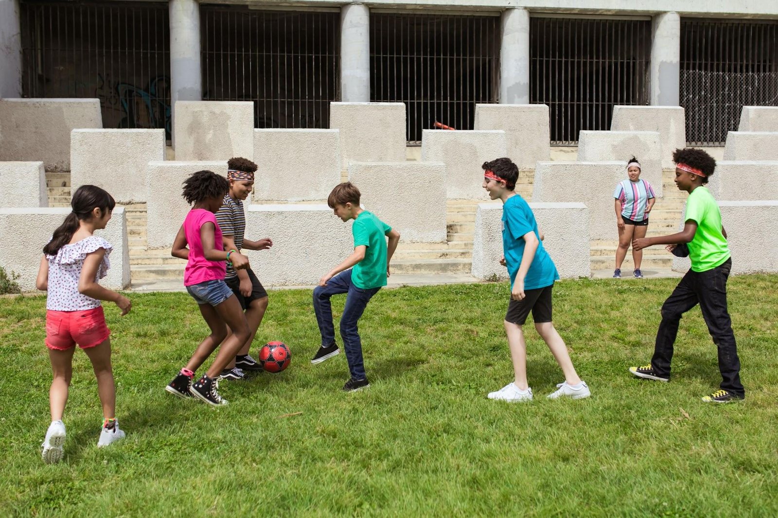 Diverse group of children playing soccer together on a grass field